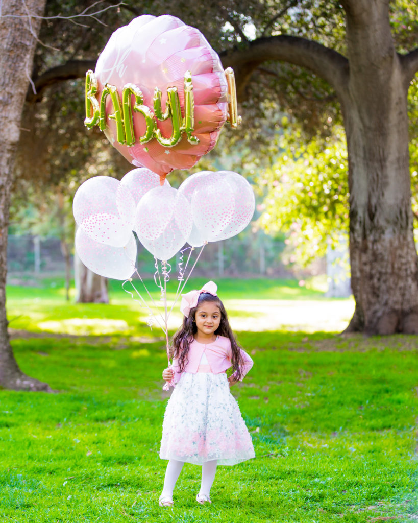 little girl with balloons waiting for his brother